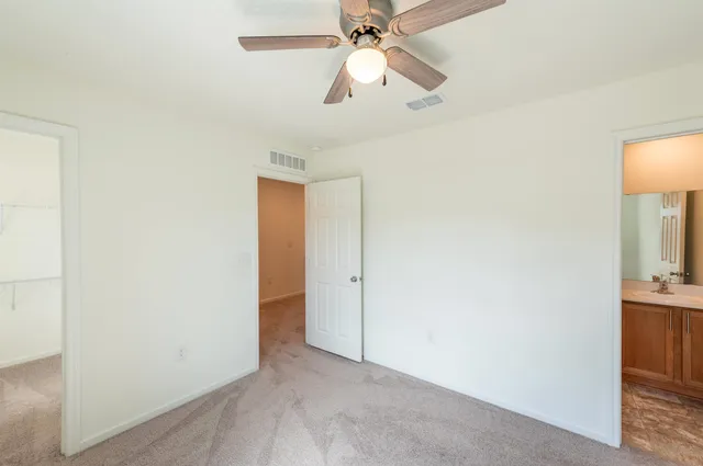 an empty room with closet and a chandelier fan