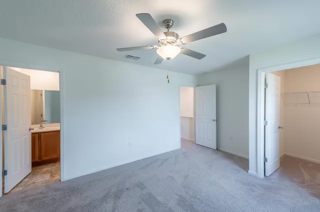 an empty room with closet and a chandelier fan