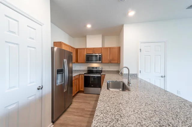 a kitchen with stainless steel appliances granite countertop a refrigerator sink and stove