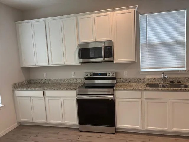 a kitchen with granite countertop white cabinets and stainless steel appliances