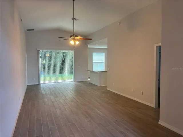 an empty room with wooden floor chandelier and windows