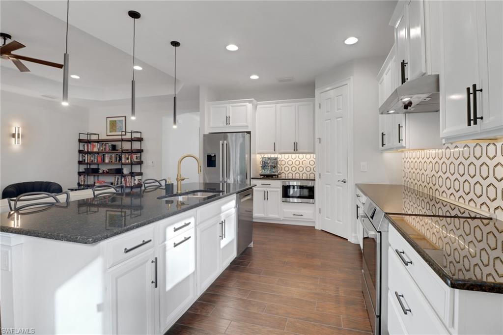 14374 Tuscany Pointe Trail Naples, FL 34120 - Photo 13 of 38 a kitchen with kitchen island granite countertop a sink a counter top space stainless steel appliances and cabinets