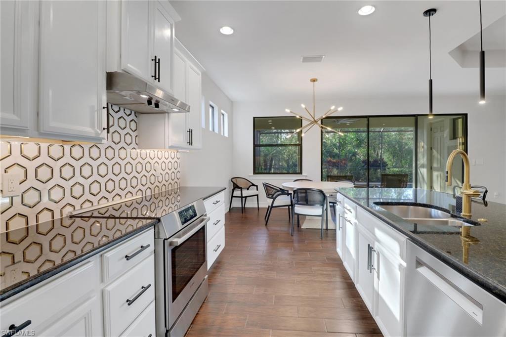 14374 Tuscany Pointe Trail Naples, FL 34120 - Photo 14 of 38 a kitchen with stainless steel appliances granite countertop a sink a stove and a wooden floors