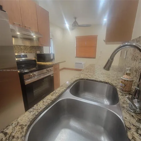 a kitchen with granite countertop a sink a stove and a refrigerator
