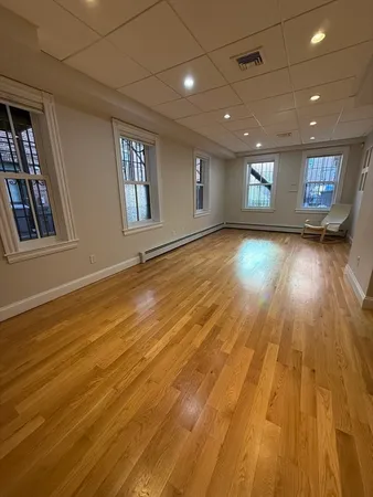 a view of an empty room with window and wooden floor