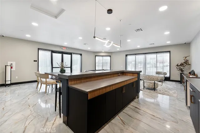 a large kitchen with kitchen island a large counter top space a sink a stove and a window