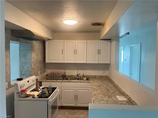 a kitchen with granite countertop stainless steel appliances sink stove and cabinets