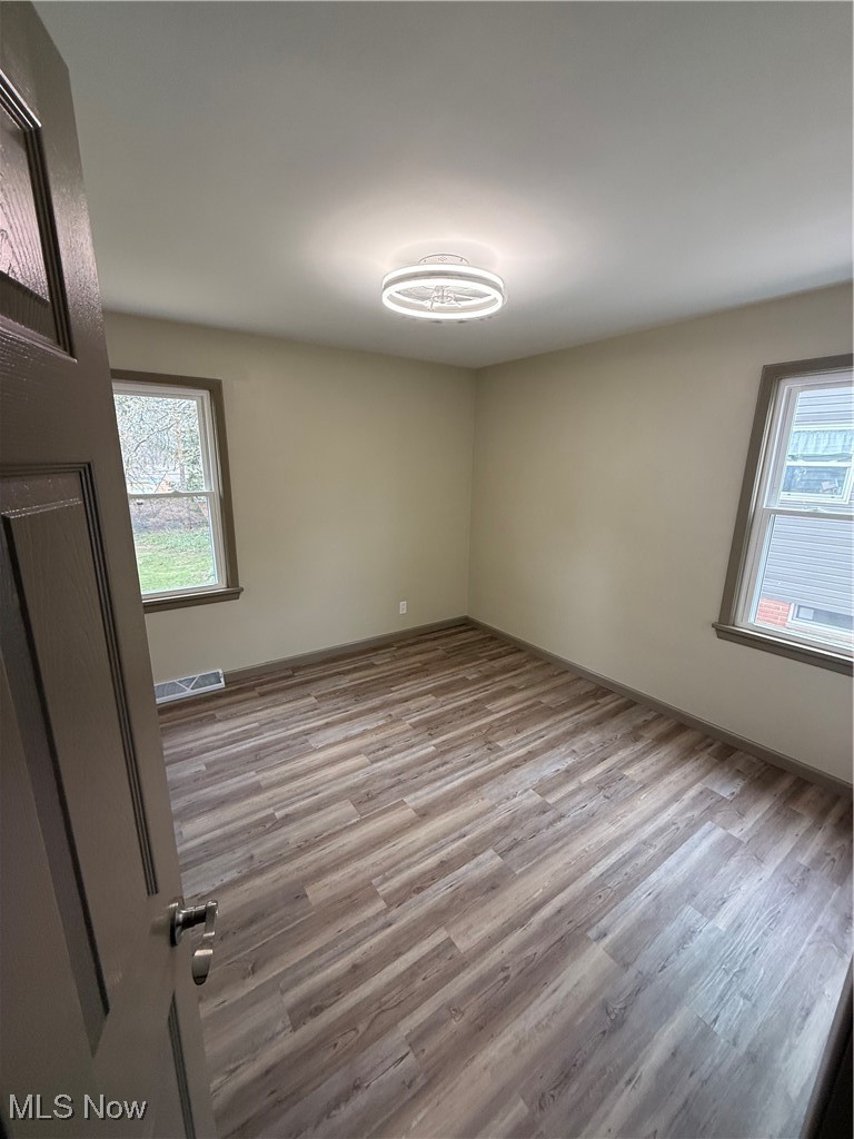 9417 Alexander Road Garfield Heights, OH 44125 - Photo 20 of 38 Spare room featuring visible vents, wood finished floors, and a healthy amount of sunlight