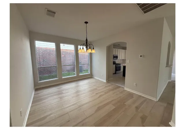 a view of an empty room with window and wooden floor