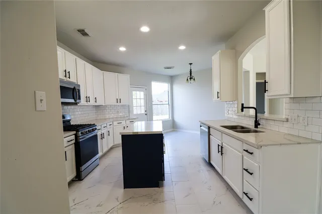 a kitchen with stainless steel appliances granite countertop a stove top oven a sink a counter space and cabinets