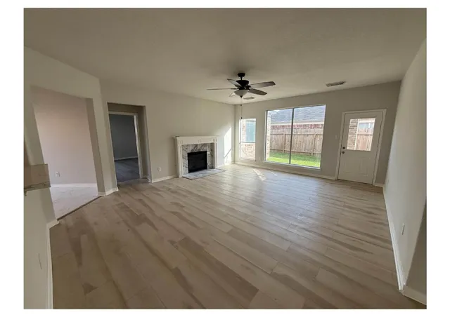 a view of empty room with wooden floor and fan