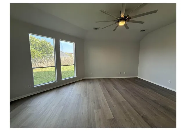 an empty room with wooden floor and windows