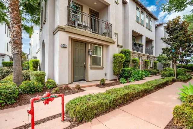 a front view of a multi story residential apartment building with yard and sign board