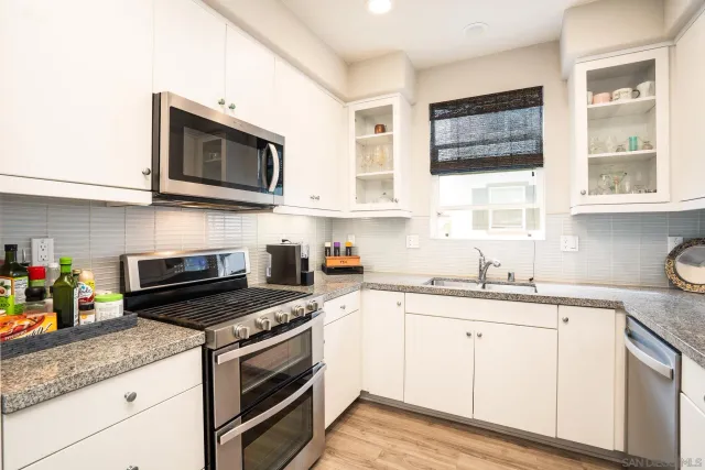 a kitchen with stainless steel appliances granite countertop white cabinets a sink and a stove