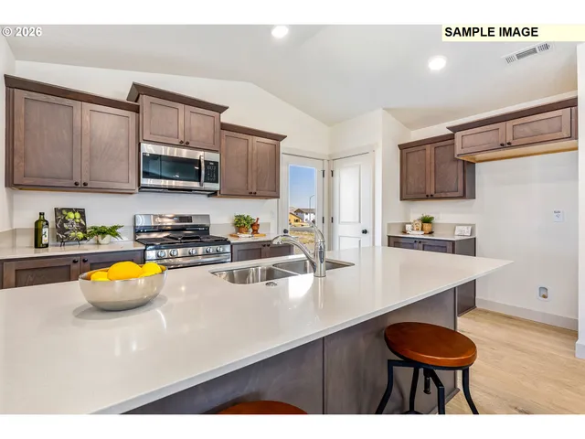 a kitchen with stainless steel appliances a stove a sink a microwave a refrigerator and cabinets