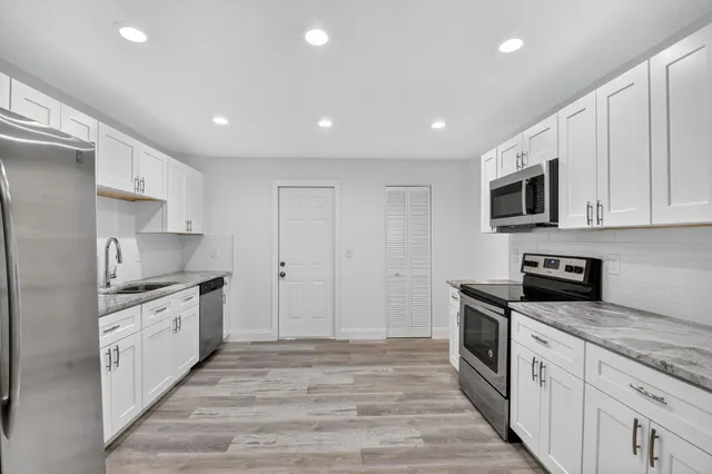 a kitchen with stainless steel appliances granite countertop a stove top oven a sink and a refrigerator