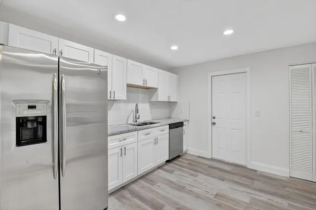 a kitchen with white cabinets and refrigerator