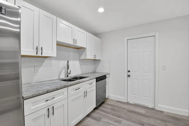 a kitchen with granite countertop white cabinets and a sink