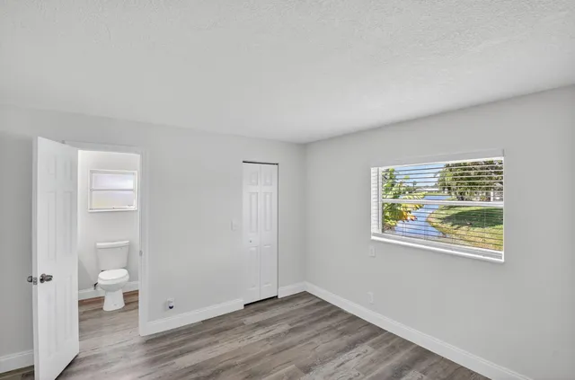 a view of an empty room with a window and wooden floor