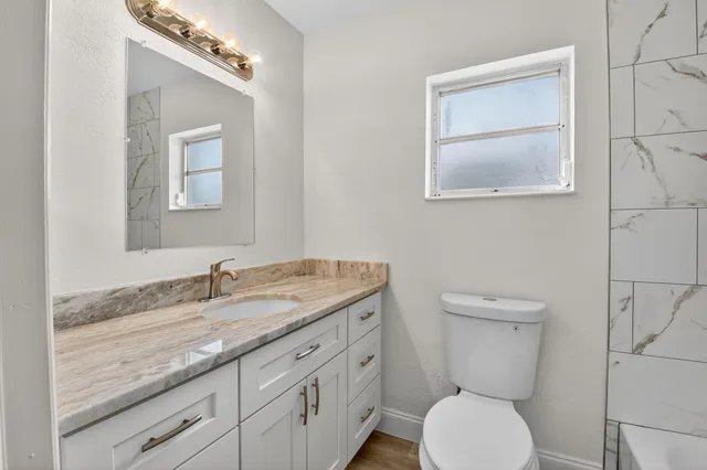 a bathroom with a granite countertop toilet sink and mirror