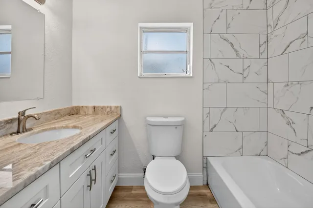 a bathroom with a granite countertop sink toilet and shower