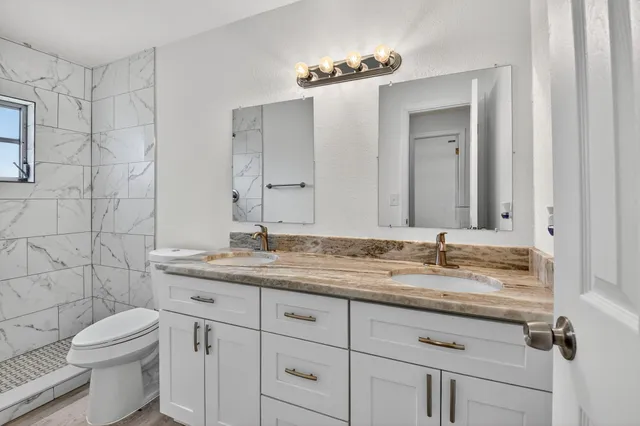 a bathroom with a granite countertop sink a toilet and a mirror