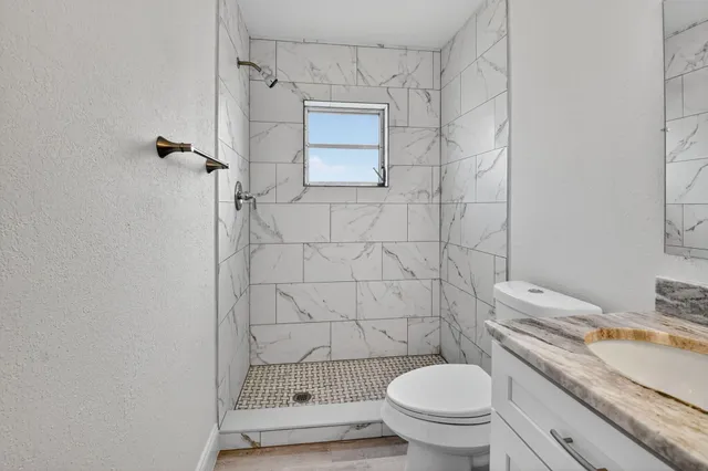a bathroom with a granite countertop toilet and a shower