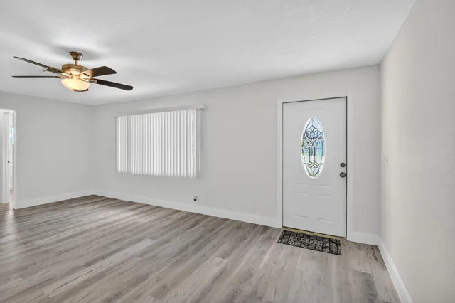 an empty room with windows and fan