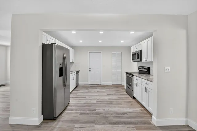 a view of a kitchen with a sink and dishwasher a refrigerator with wooden floor