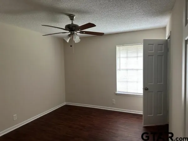 an empty room with wooden floor closet and windows