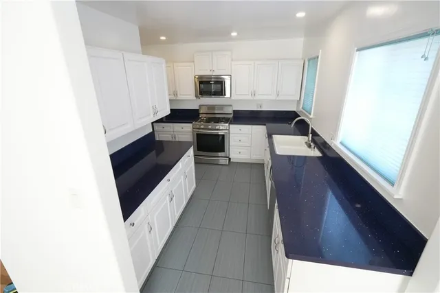 a large kitchen with a sink a microwave and cabinets