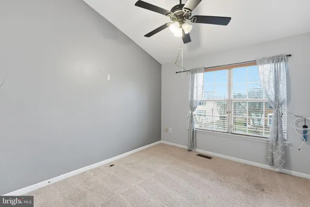 a view of an empty room and chandelier fan