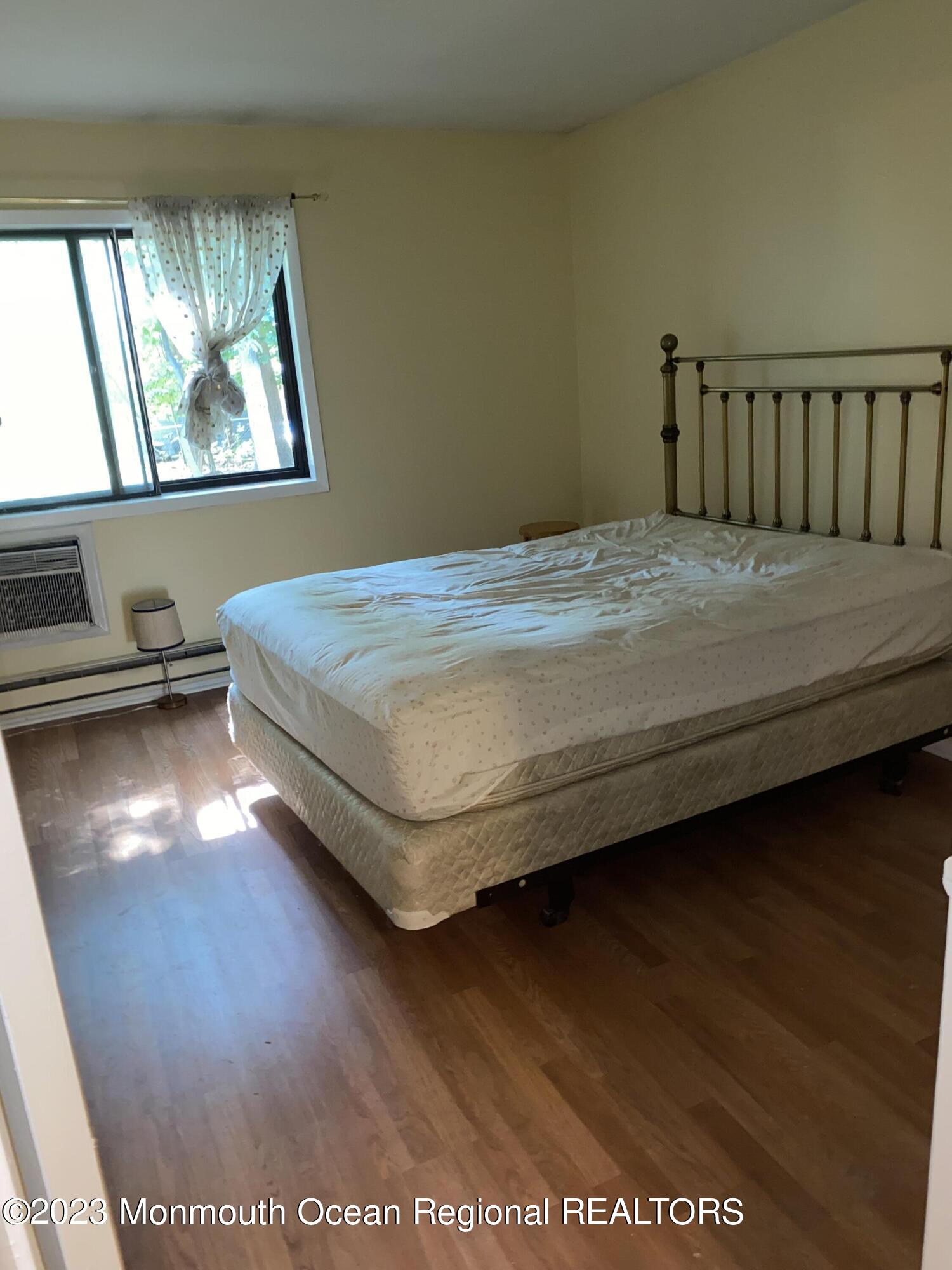 91 Arrowood Road, Unit E Manalapan, NJ 07726 - Photo 8 of 8 a bed sitting in a bedroom next to a window