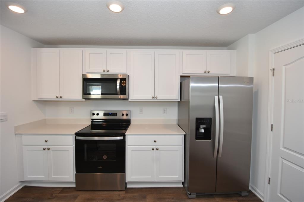 9 Springwood Drive Palm Coast, FL 32137 - Photo 10 of 29 a kitchen with white cabinets and stainless steel appliances
