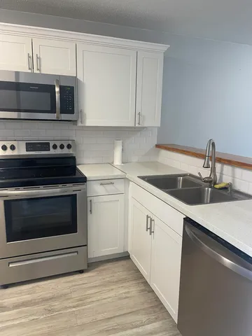 a kitchen with stainless steel appliances a stove a microwave a sink and cabinets