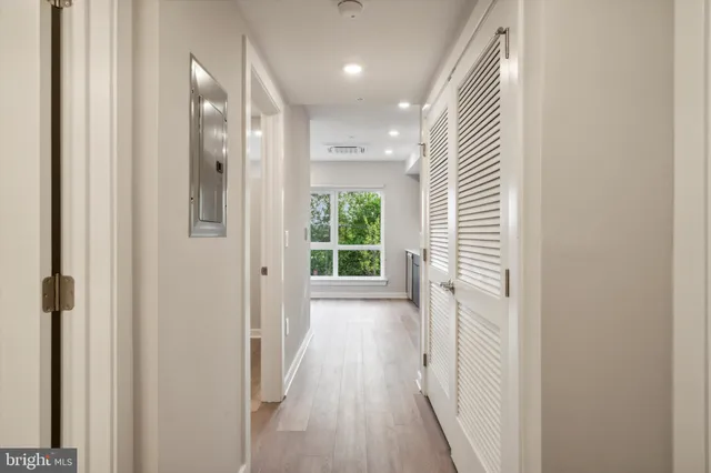 a view of a hallway with wooden floor and a bathroom