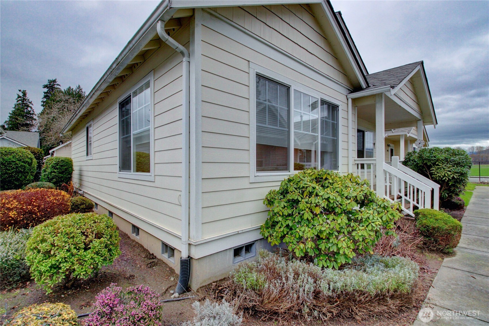 1072 Sinclair Way, Unit 56 Burlington, WA 98233 - Photo 3 of 29 a view of a house with brick walls and flower plants