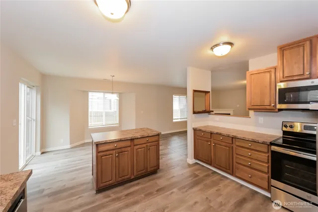a kitchen with stainless steel appliances granite countertop a stove a sink and a microwave