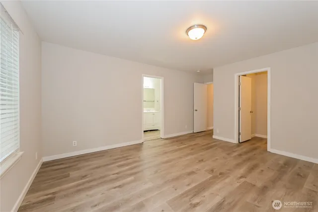 a view of an empty room with wooden floor and window