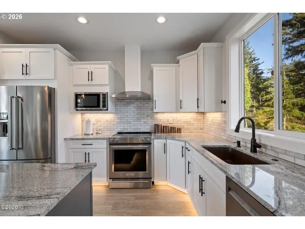 a kitchen with stainless steel appliances granite countertop a sink stove and refrigerator