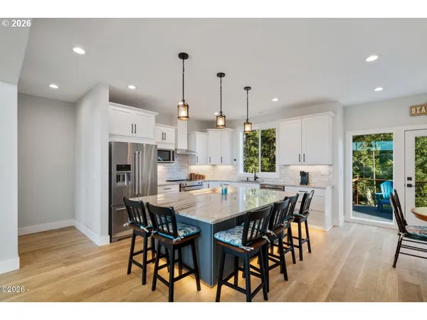 a view of a dining room and livingroom with furniture wooden floor a rug a rug a fireplace and a chandelier