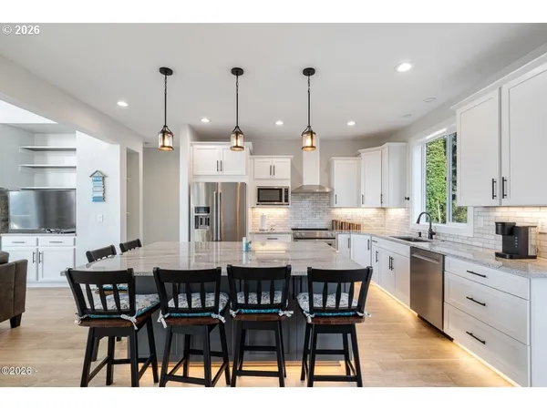 a kitchen with stainless steel appliances kitchen island granite countertop a dining table chairs and sink