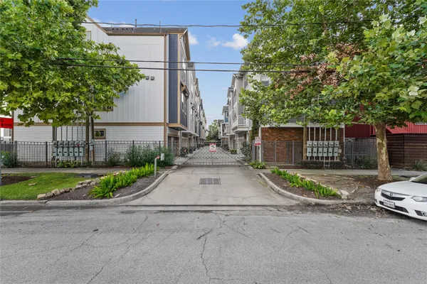 a white house with a small yard plants and big trees