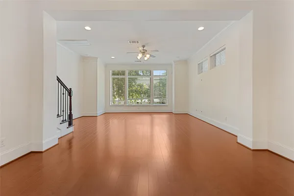 an empty room with wooden floor and windows