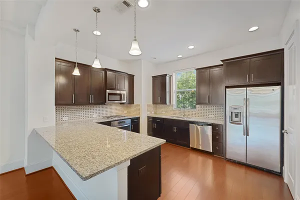 a kitchen with stainless steel appliances granite countertop a refrigerator a sink and a microwave