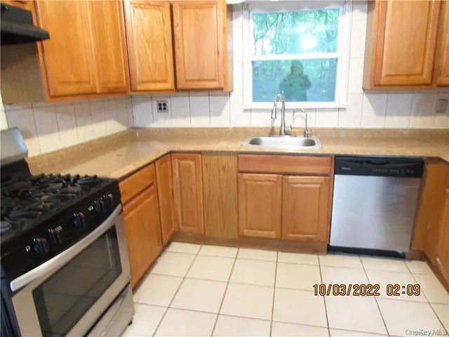 a kitchen with a sink a stove cabinets and window