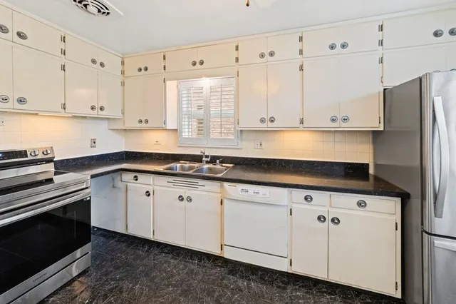 a kitchen with granite countertop white cabinets and a stove