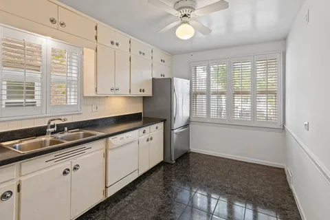 a kitchen with granite countertop a sink window and cabinets