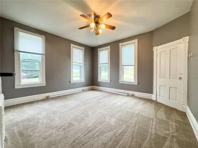 an empty room with windows and ceiling fan
