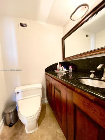 a bathroom with a granite countertop toilet sink and mirror